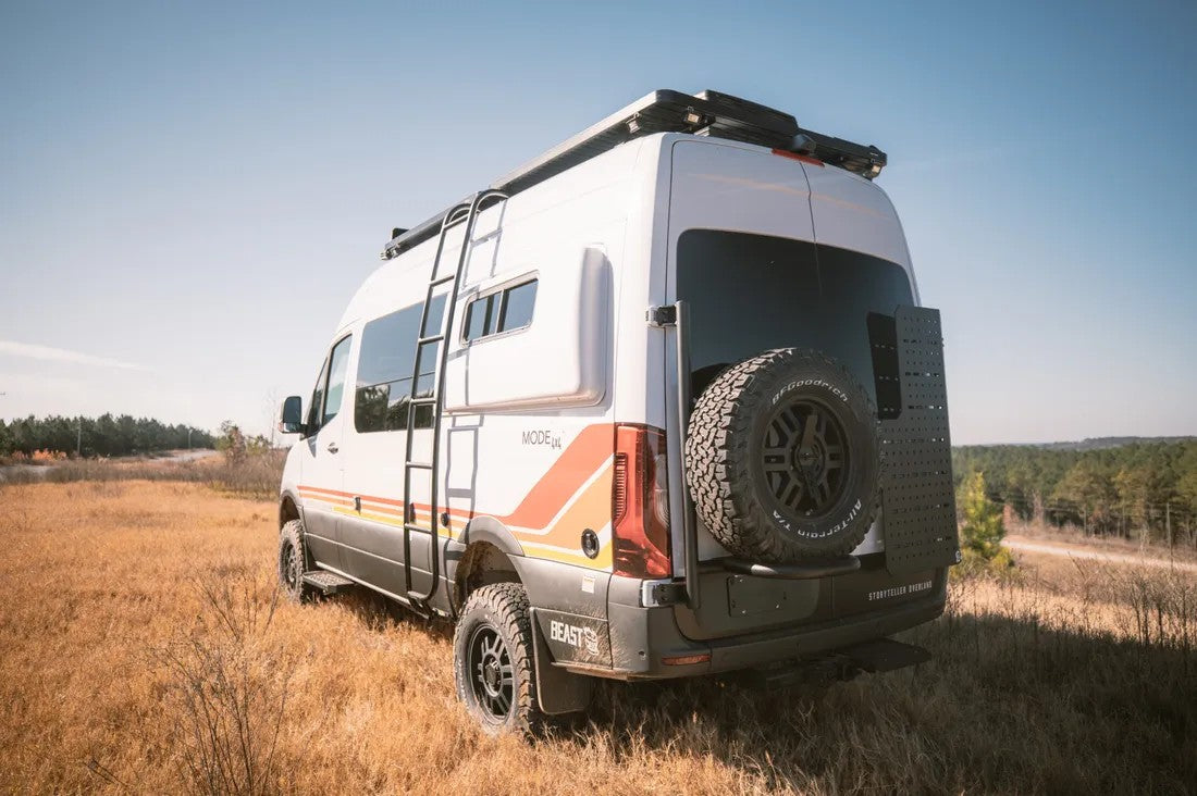 Rugged white Storyteller Overland adventure van with ladder, roof rack, and rear spare tire, ideal for an rv rental outdoor escape.