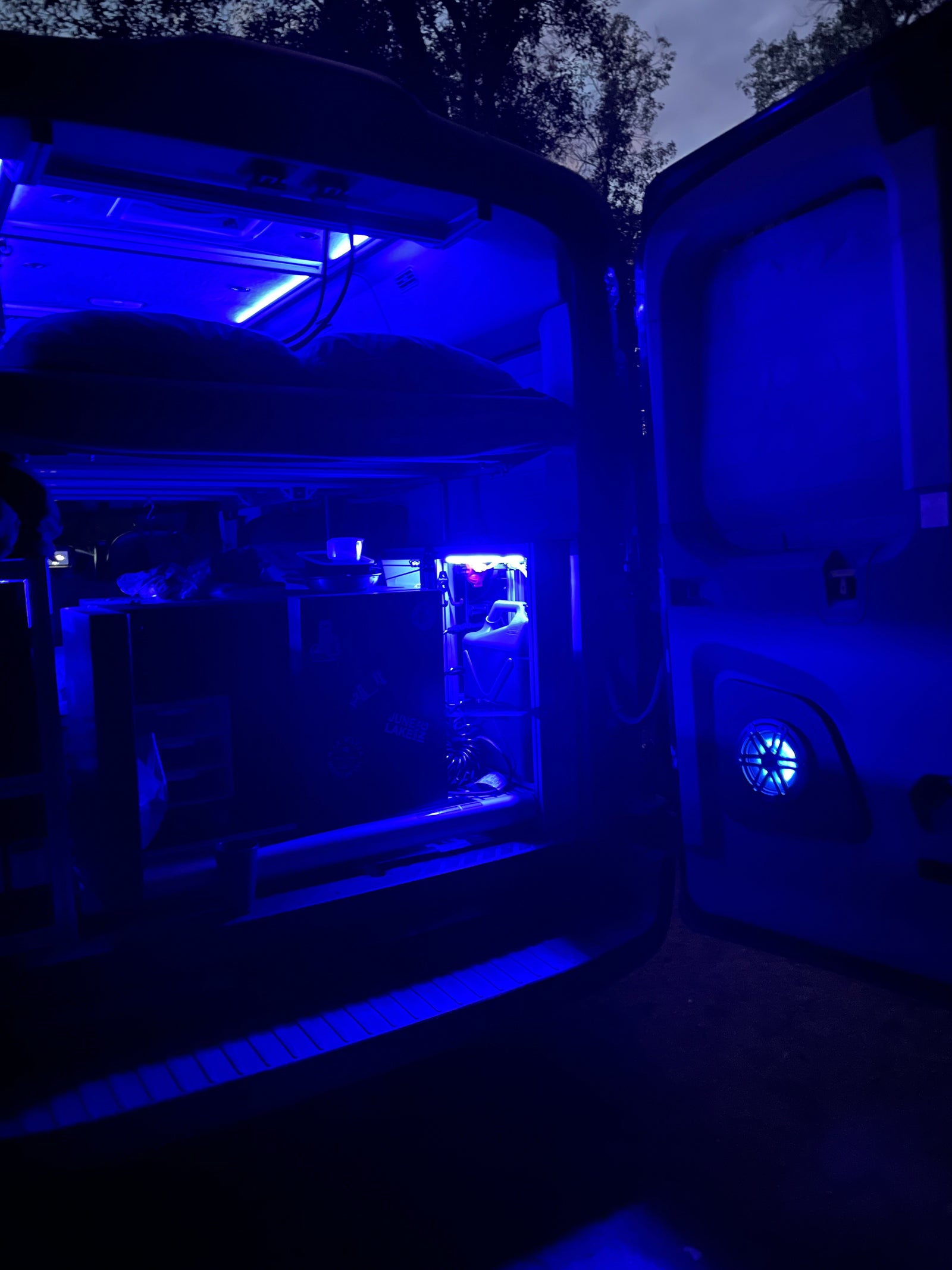 Blue-lit RV rental interior at night, showcasing a custom computer setup. Perfect for unique tech travel experiences.