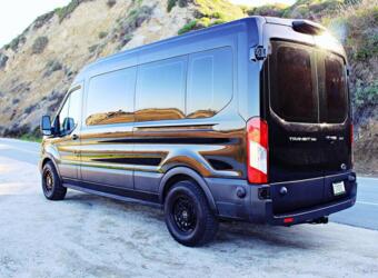  is parked outdoors. Perfect for your next road trip adventure.|This black Ford Transit van — photo 4