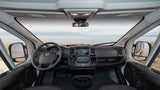 RV rental: Inside a camper van's cockpit, showing the dashboard, steering wheel, and a scenic waterfront view ahead.