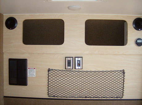 This RV rental interior shows light wood panels, overhead storage, speakers, power outlets, and a propane safety warning.