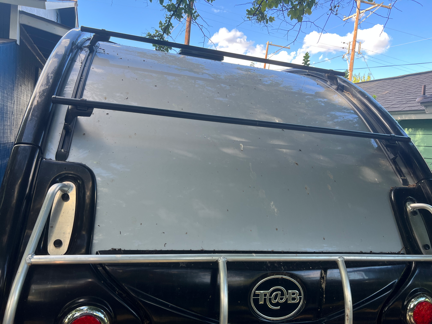 Rear view of a T@B camper with a roof rack, featuring a light grey roof and black body, ideal for rv rental.