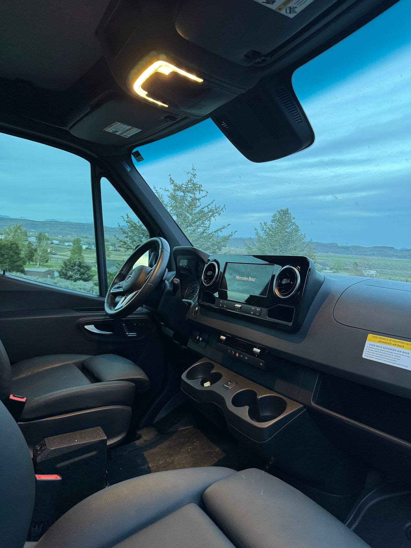 Modern Mercedes-Benz rv rental interior with dashboard, steering wheel, and a scenic view through the windshield.