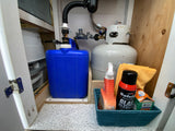 RV rental cabinet: a grey water tank, propane tank, and cleaning supplies neatly stored below the sink.