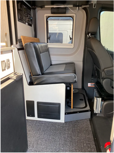 RV rental interior view showcasing a bench seat, window, and systems control panel.