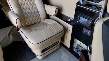 RV rental luxury interior with cream quilted leather captain's chair, built-in entertainment system, and climate controls.