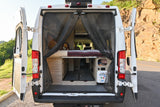 This RV rental's rear is open, showing a mesh screen, a raised bed, and built-in storage, ideal for campervan living.