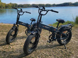 Two Jasion folding fat tire e-bikes by a lake. Ideal for RV rental trips, offering versatile outdoor exploration.