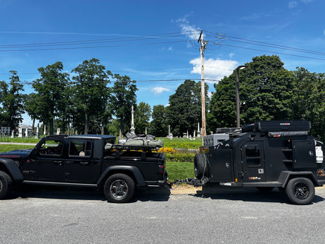 Black Jeep Gladiator towing an Off Grid overland trailer with a Roofnest tent, an ideal RV rental for rugged adventures.