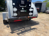 RV rental: Rear of white travel trailer. Features black cargo rack, bright red LED taillights, and off-road tire. Ready for adventure.