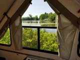 Inside an RV rental, enjoy a tranquil lake view with lush green trees and calm waters, framed by interior trim and "EXIT" signs.