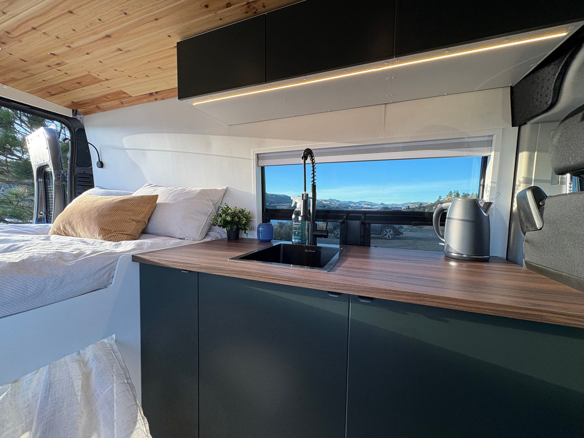 Cozy RV rental camper van interior: modern kitchen, comfy bed, & scenic mountain views through the window. Ideal for road trips. — photo 10