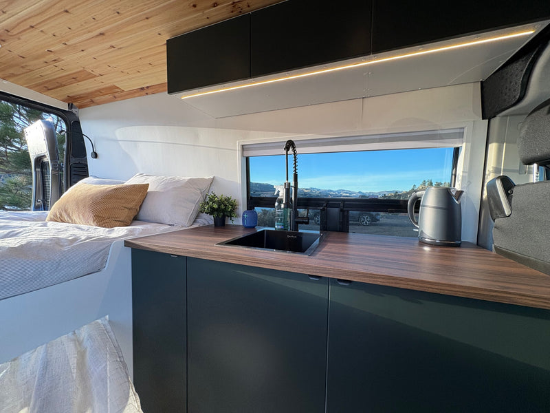 Cozy RV rental camper van interior: modern kitchen, comfy bed, & scenic mountain views through the window. Ideal for road trips. — photo 10
