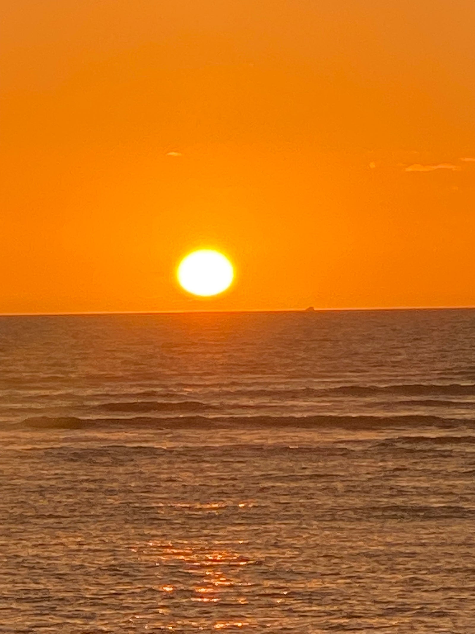 A radiant golden sunset over the vast ocean, with gentle waves reflecting the light. Your RV rental awaits this view!