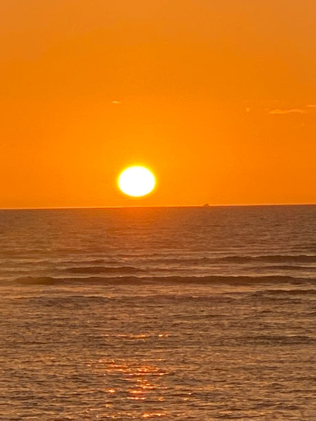 A radiant golden sunset over the vast ocean, with gentle waves reflecting the light. Your RV rental awaits this view!