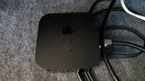A dusty black Apple TV device, connected to cables on a gray textured surface, ready for your RV rental entertainment.