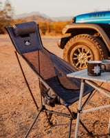 Relaxing outdoor setup: portable chair, table, and mug by a rugged vehicle, ideal for your next RV rental adventure.