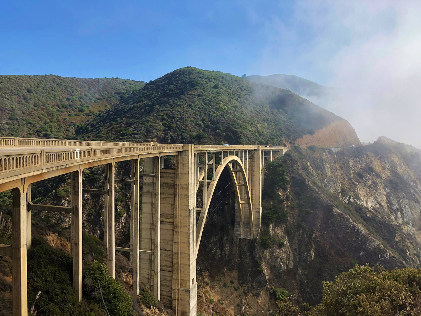 Iconic Bixby Bridge on the California coast, with lush mountains & fog. Perfect for an RV rental scenic drive.