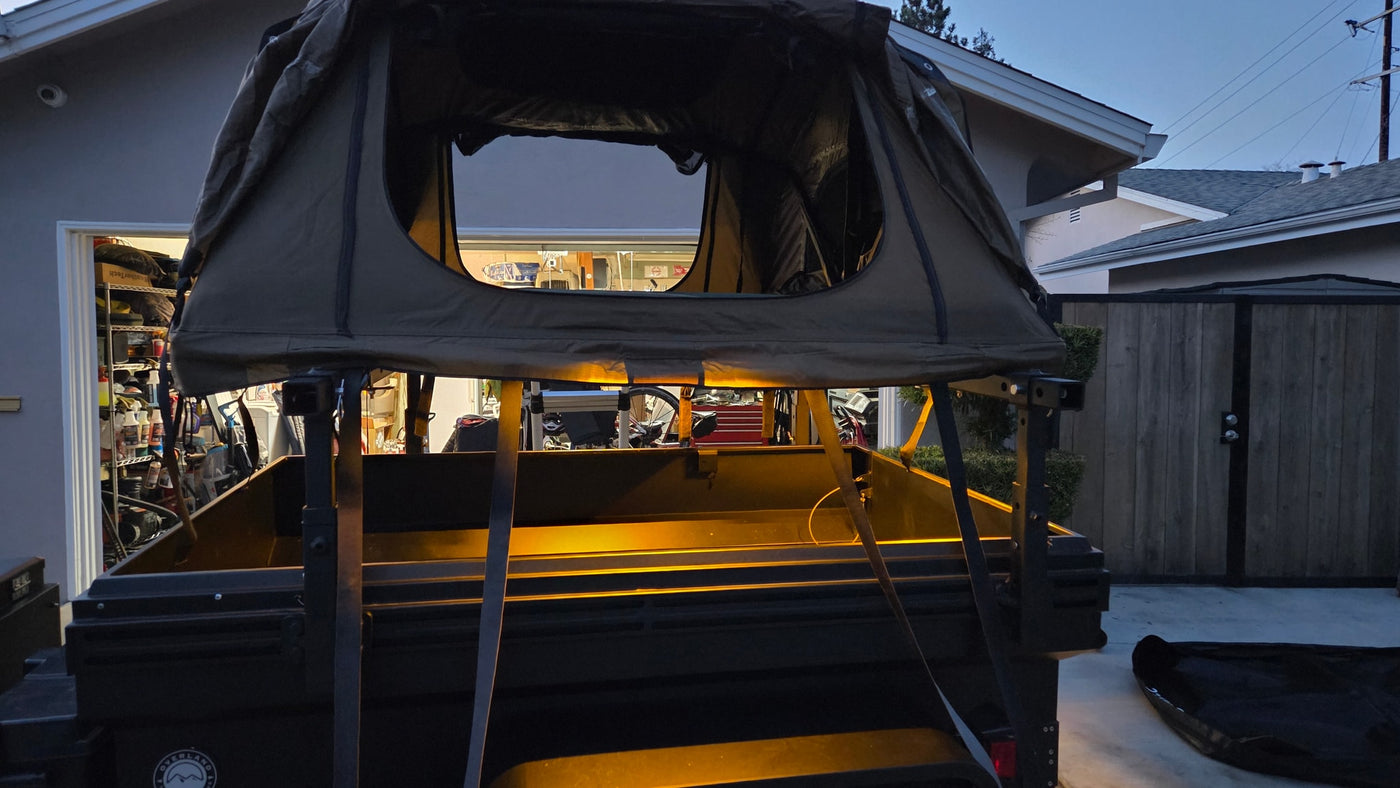 Rooftop tent deployed on an overland trailer, with garage visible behind. Ideal rv rental for camping adventures. — photo 6