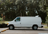 A white cargo van with a surfboard fin on its roof, an ideal RV rental for surf trips and outdoor adventures.