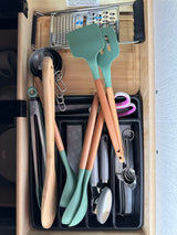 RV rental kitchen drawer neatly organized with cooking utensils: green spatulas, measuring tools, a grater, and more.