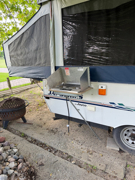 Pop-up camper RV rental with an outdoor stove & fire pit, perfect for a campout.