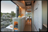 Modern RV rental interior with kitchen, dining area, and scenic desert view out the open back doors.