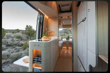 Modern RV rental interior with kitchen, dining area, and scenic desert view out the open back doors.