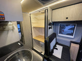 This RV rental features a compact kitchen, a versatile wet bath with toilet, and comfortable passenger seating in a modern interior.