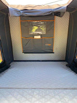 Comfortable, quilted interior of a Roofnest rooftop tent, ideal for RV rental trips. Features storage pockets and a clear window.