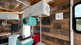RV rental kitchen: wood walls, white cabinets, retro mint microwave, coffee maker, cooktop, and nautical decor.