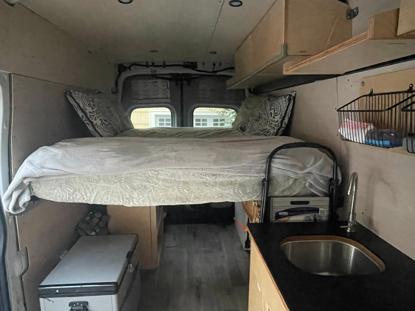 Experience mobile living! This RV rental features a cozy raised bed, compact kitchen with sink, and fridge, ideal for adventures. — photo 5