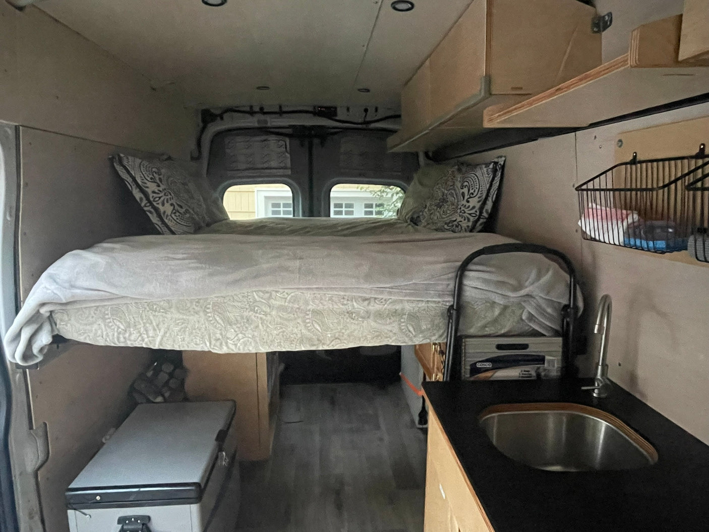 Experience mobile living! This RV rental features a cozy raised bed, compact kitchen with sink, and fridge, ideal for adventures.