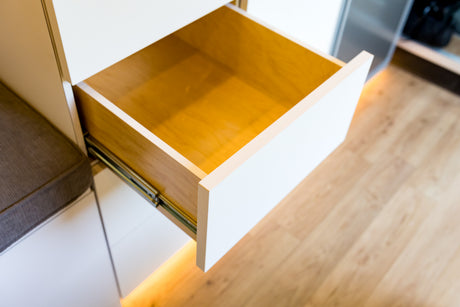 RV rental storage: An open wooden drawer with white trim and subtle under-cabinet lighting, showcasing compact interior space.