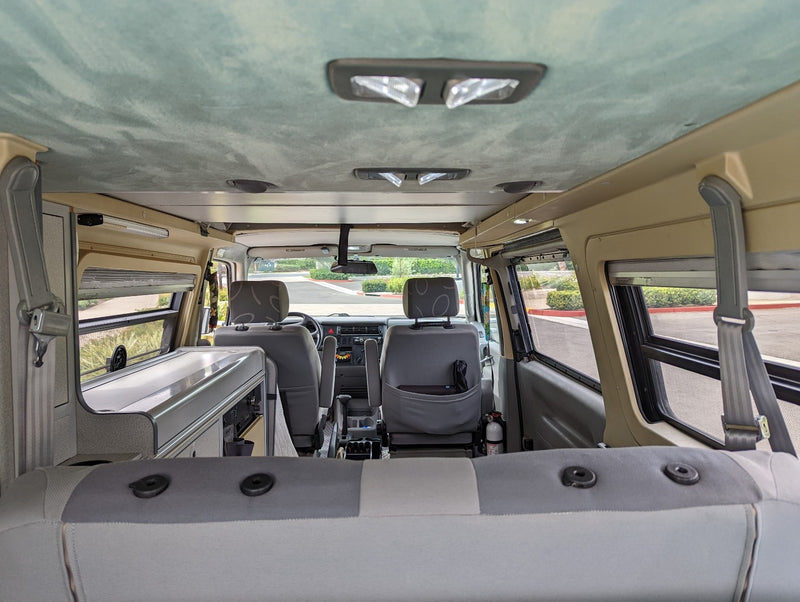 Spacious RV rental camper van interior, featuring front seats and a compact kitchen from a rear view. — photo 6
