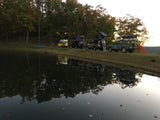 A serene pond reflects three adventure-ready RVs with rooftop tents. Experience overlanding with an RV rental.