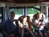 Family enjoying their RV rental: Dad and two boys, one playing a handheld game, are seated inside.