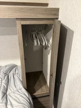Compact RV rental closet with hangers, adjacent to a bed, offering practical storage in a small space for travelers.