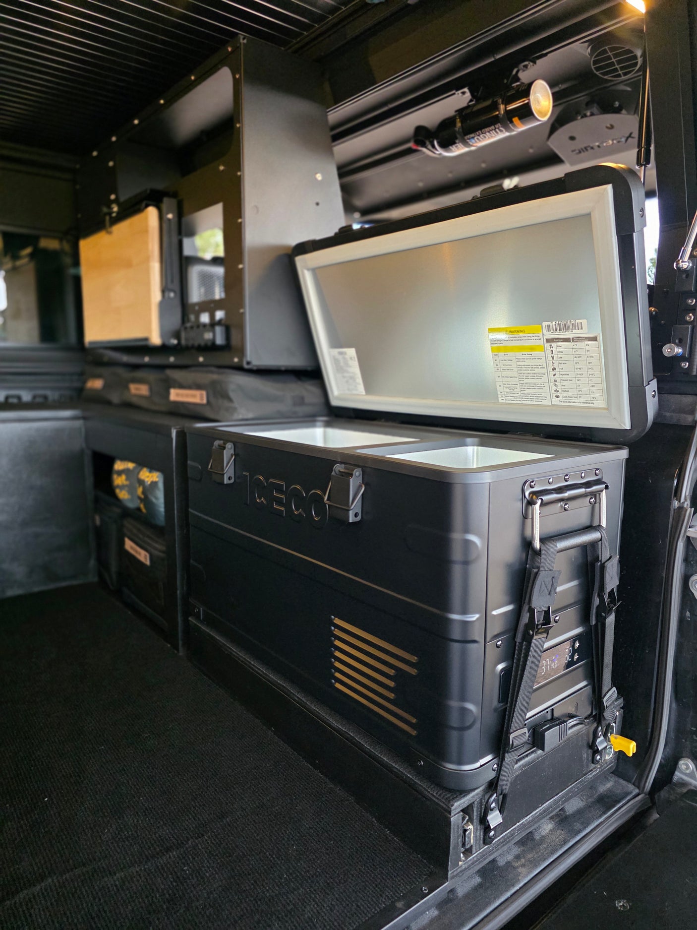 This RV rental's organized interior features an ICECO fridge/freezer, modular storage, and a safety extinguisher.