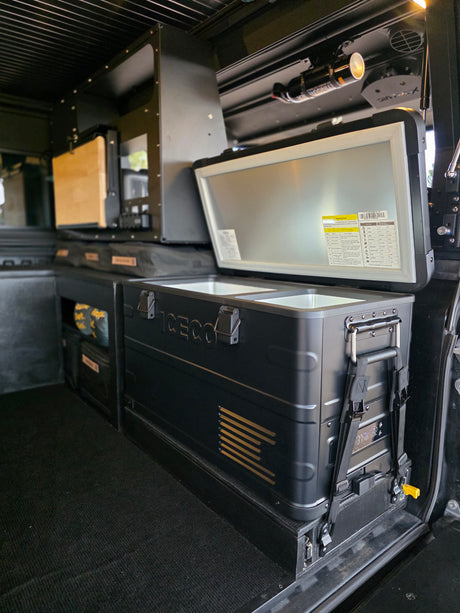 This RV rental's organized interior features an ICECO fridge/freezer, modular storage, and a safety extinguisher.