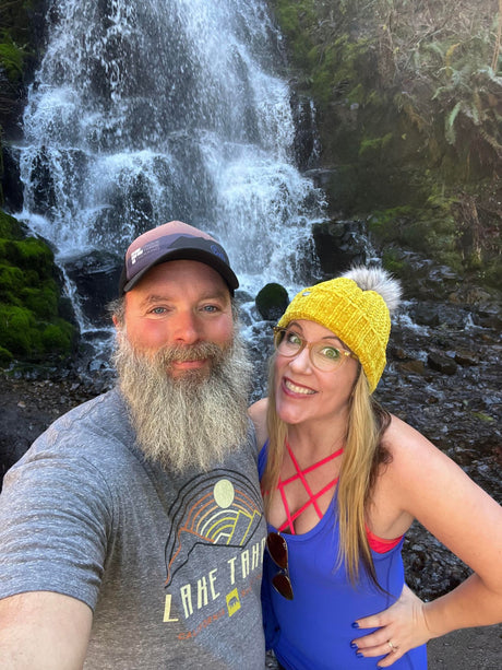 Smiling couple by a beautiful waterfall, a perfect RV rental adventure stop on their journey.