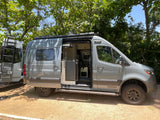 Experience adventure! This modern grey Winnebago camper van, an ideal RV rental, features an open side door & functional interior.