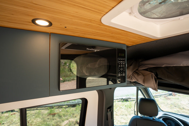 RV rental interior: handy overhead microwave, sleek cabinetry, and lighting for your journey. — photo 9