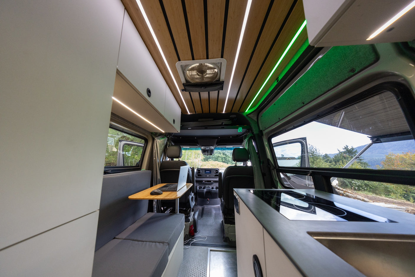 Modern rv rental interior with kitchen, workspace, and scenic outdoor views through windows.