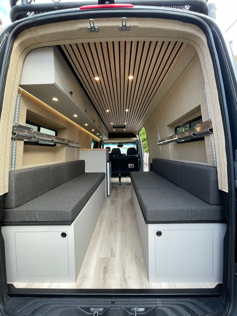  and lush hills.|Scenic RV rental setup: remote work with coffee & laptop overlooks a bustling coastal harbor & hills.|Kids enjoying card games in a cozy RV rental interior. Perfect for family adventures on the road.|Adventure-ready RV rental van with roof rack — photo 8