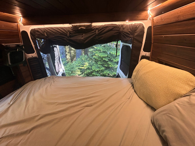Cozy RV rental bedroom looking out to a lush forest view, perfect for a nature getaway or camping trip in your camper van. — photo 15
