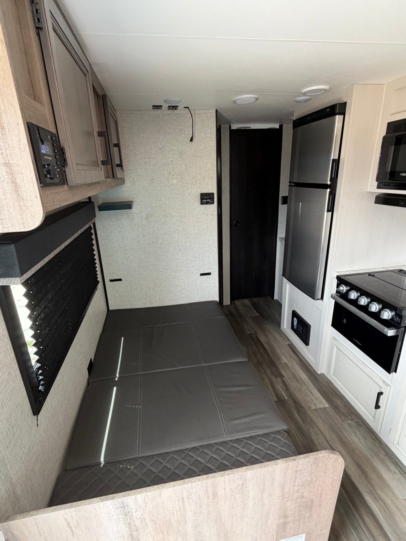 RV rental interior: compact kitchen (fridge, stove, microwave) and bed/seating area, perfect for travel.