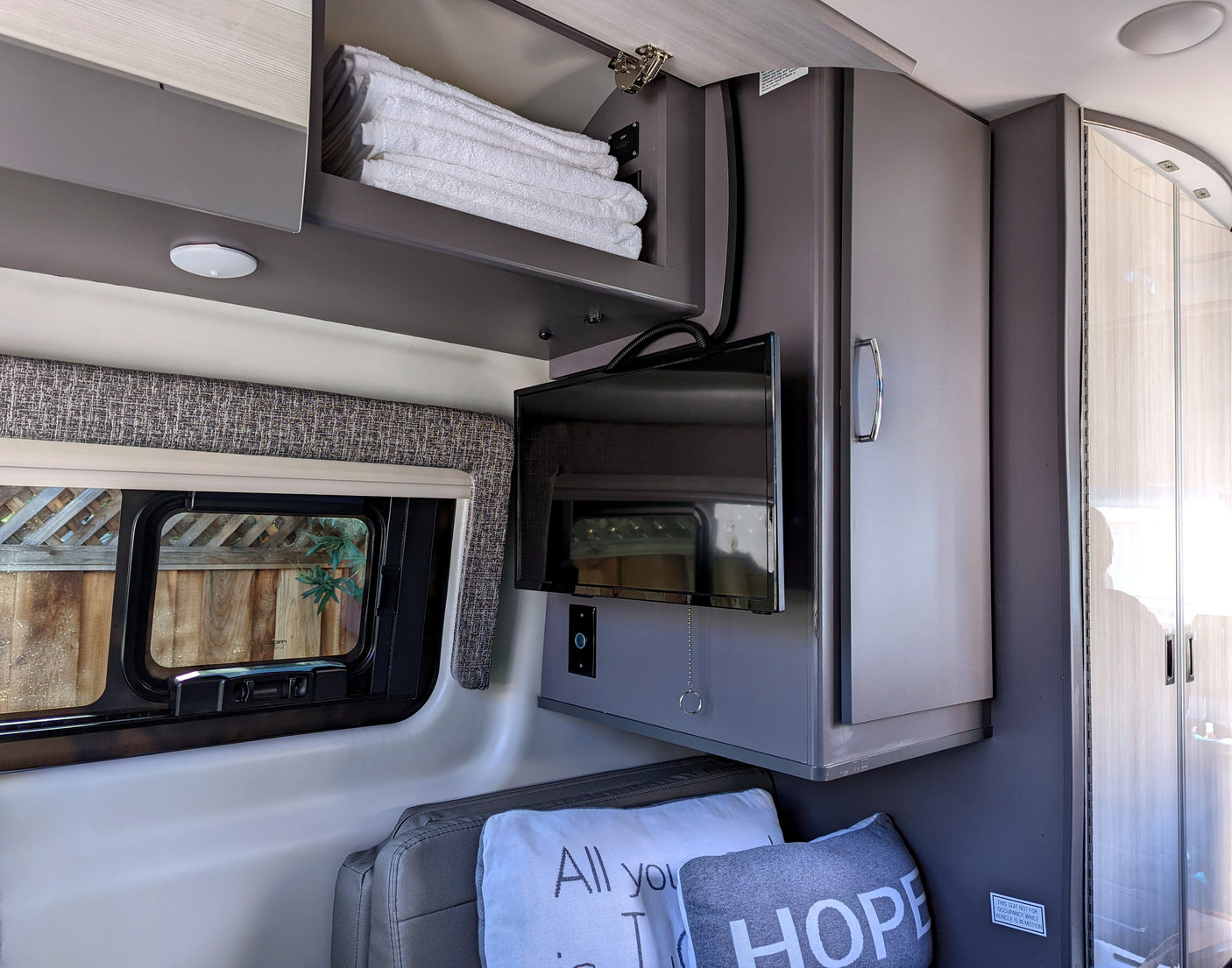 Cozy RV rental interior with TV, window, and storage for a comfortable journey.