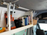 Open overhead storage in an RV rental, neatly filled with books, a Bushnell bag, and travel essentials for the road.