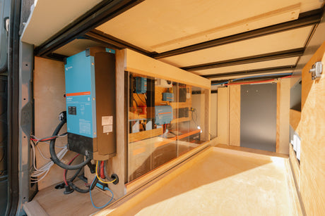 RV rental's advanced power system with Victron inverter, battery bank, and solar charge controllers in a clear enclosure.